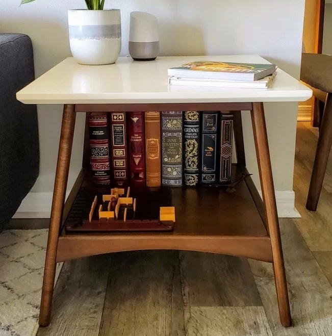 reviewer photo of the white and wood end table holding books and a vase