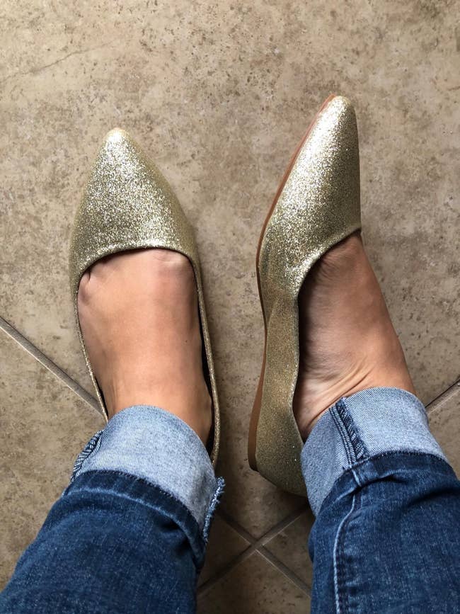 Person wearing glittery pointed-toe flats and rolled-up jeans connected  a tiled floor