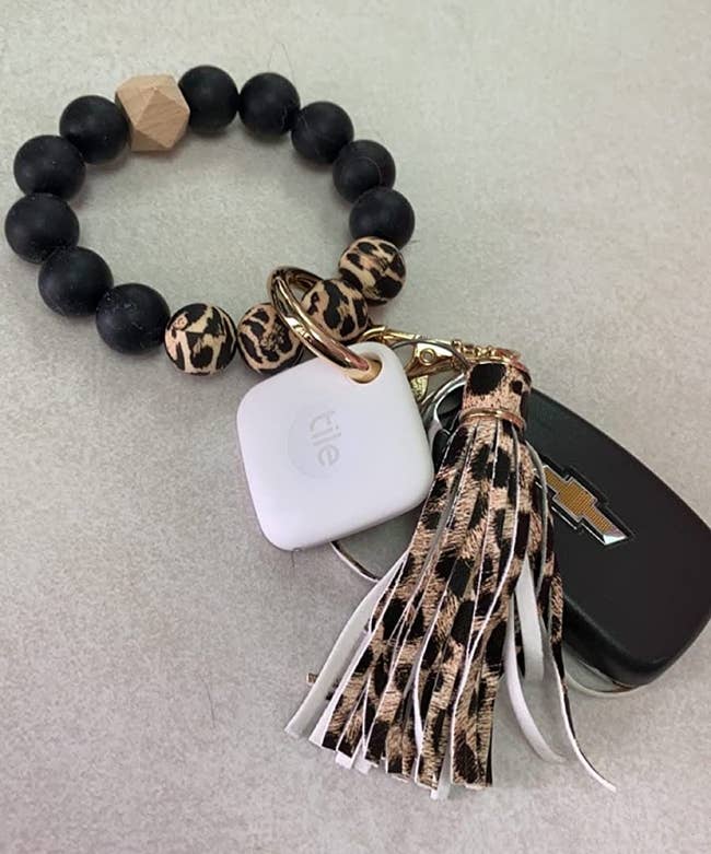 Reviewer's photo of small white square shaped tile tracker on key ring