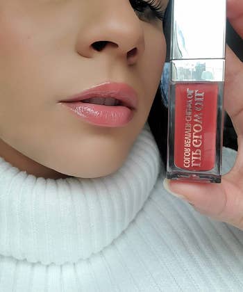 close up of reviewer wearing and holding the lip oil 