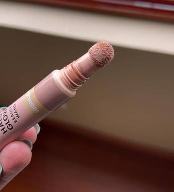 Person holding a lipstick with the applicator visible; makeup product focus