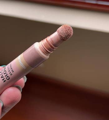 Person holding a lipstick with the applicator visible; makeup product focus