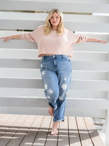 model in a pink sweater and floral jeans