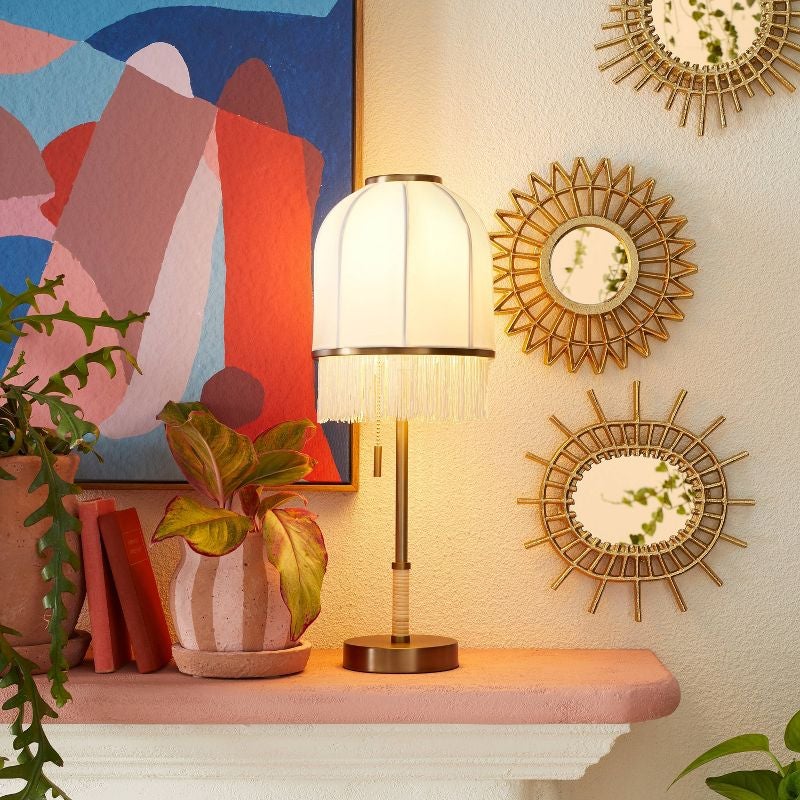 fringe white nightstand lamp lit on a mantle