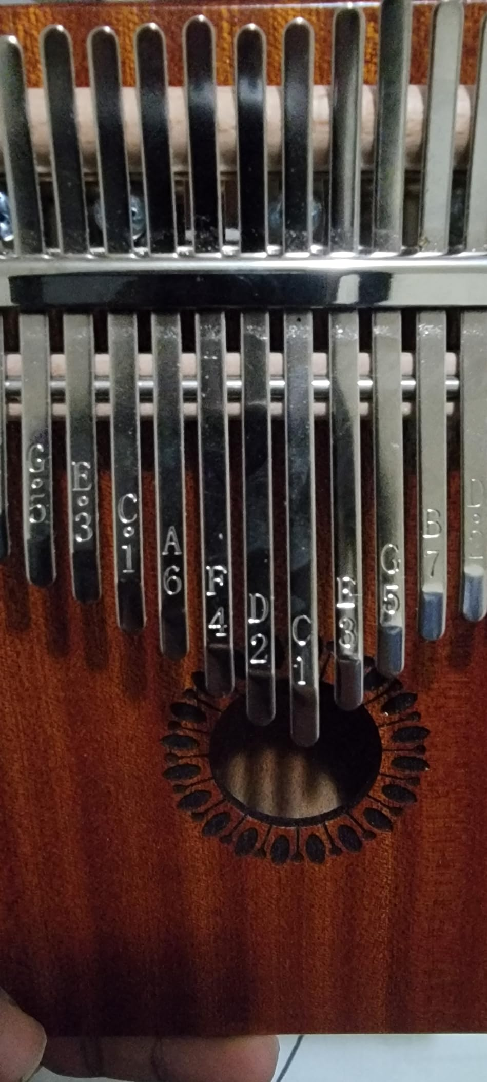 Close-up of a woody  kalimba with metallic  tines labeled with philharmonic  notes