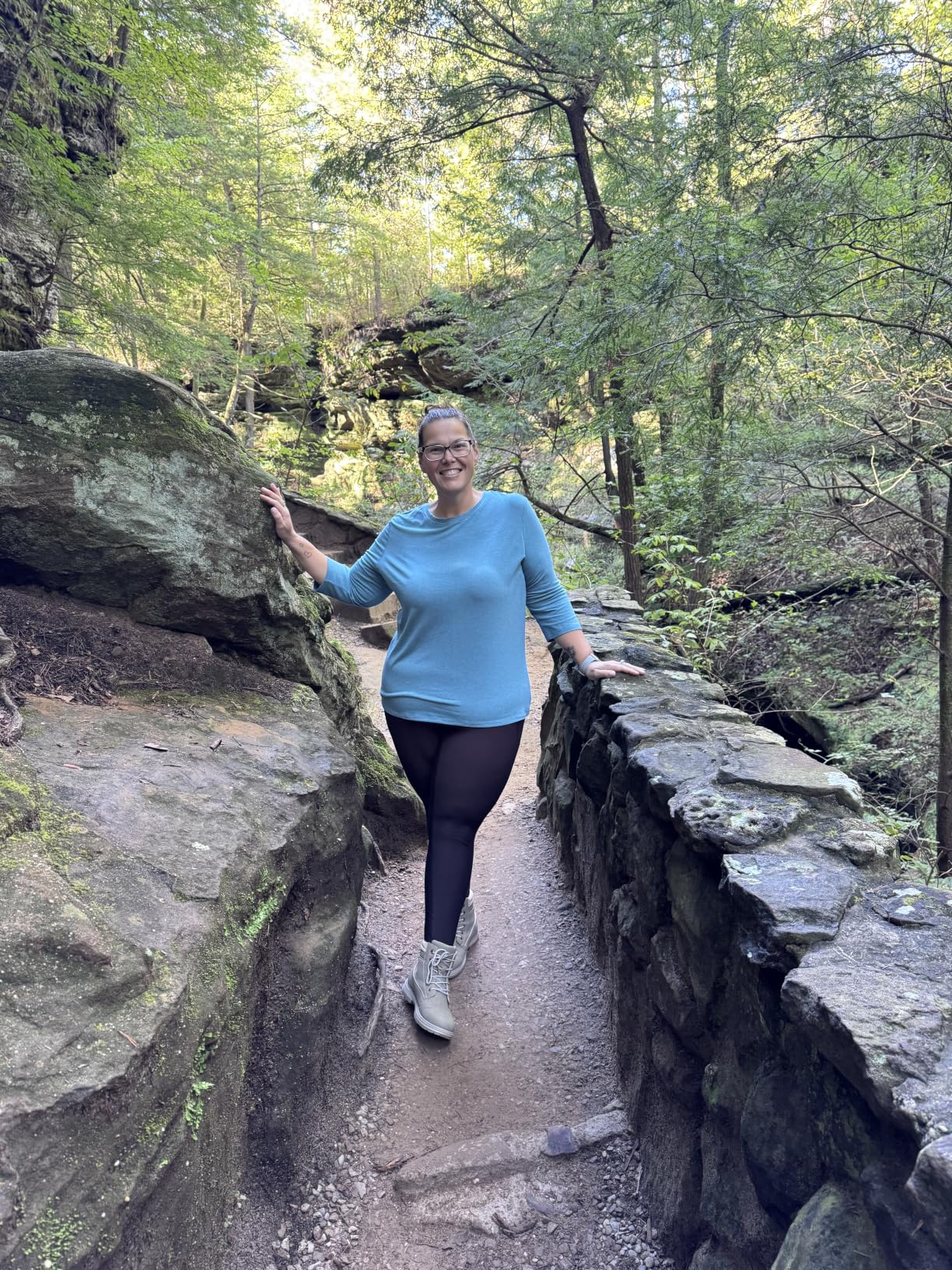 Person successful  casual outdoor attire walking connected  a wood  trail, surrounded by greenery and rocks