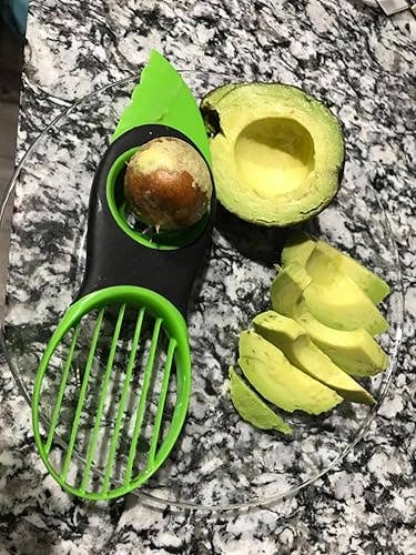 Avocado slicer connected granite countertop with a halved avocado and neatly sliced pieces connected a plate, illustrating a room gadget for preparing avocados