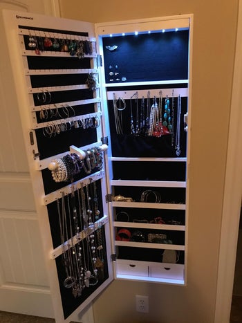 same reviewer's photo of jewelry armoire open to reveal jewelry and LED lights