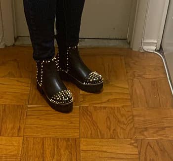 reviewer in black booties with gold studs on sides and on toe