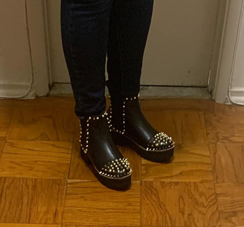 reviewer in black booties with gold studs on sides and on toe