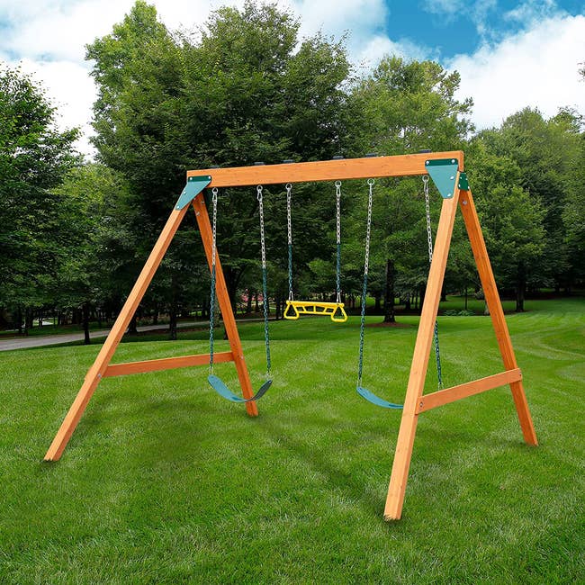a wooden swing set with two swings and one hanging bar in the middle