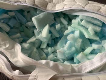 Pillow with zipper opened, revealing shredded foam filling, suitable for customizable comfort