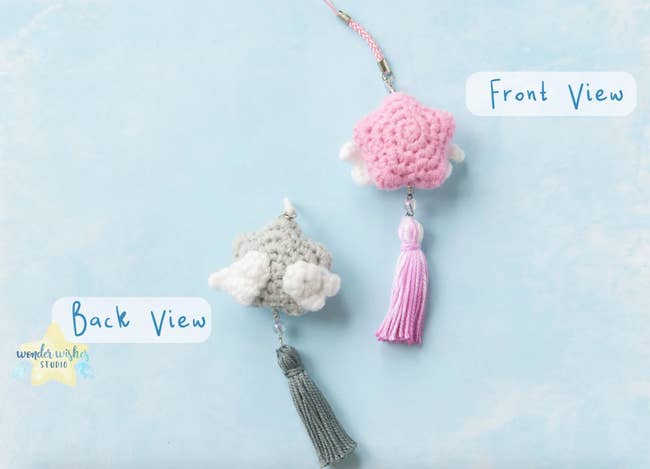 The teeny crocheted star keychain in pink and another in grey with little tassels on the bottom and white wings