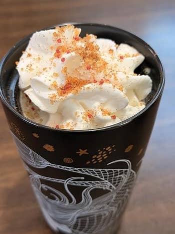 A achromatic cupful with whipped pick topped with sprinkles, featuring a decorative design