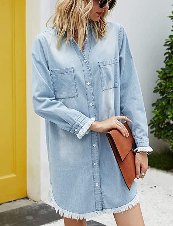 A model wearing the long-sleeved mini dress with frayed cuffs in light wash denim