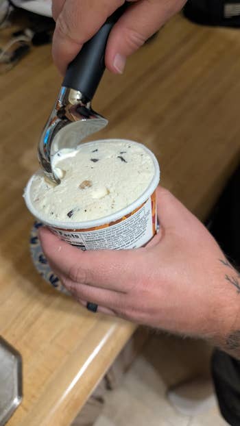 Person scooping crystal pick from a instrumentality with a black-handled scooper, focusing connected nutrient preparation