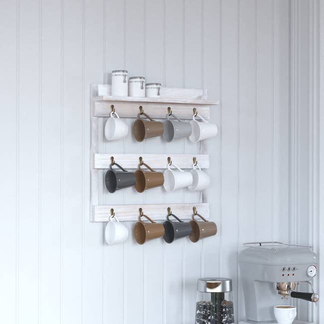 12 mugs hanging from the 12 hooks on the wall mounted mug organizer