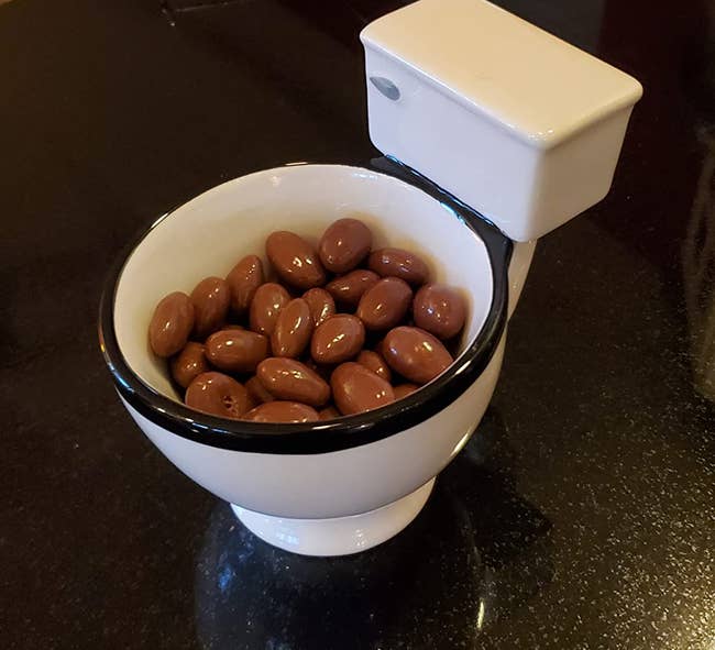 toilet shaped coffee mug with chocolate covered nuts in it