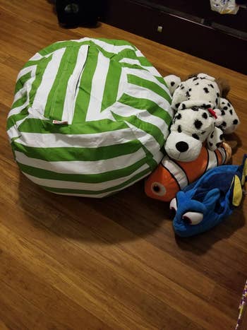 Kursi Bean Bag bergaris di sebelah mainan mewah, termasuk dalmatian, oranye clownfish, dan ikan biru, di lantai kayu