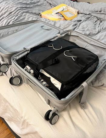 A compact black packing cube inside of a suitcase 