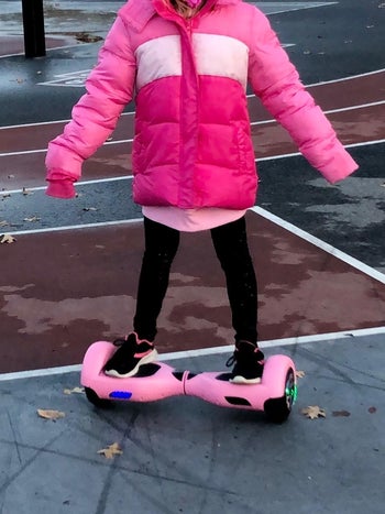 Reviewer standing on pink hoverboard on pavement