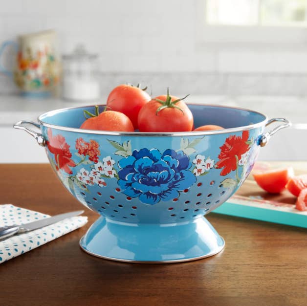 A blue colander with flowers on it and tomatoes in it