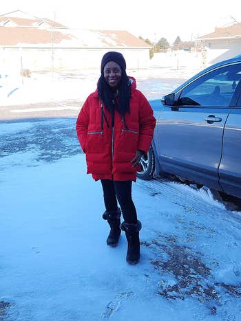 A reviewer standing in the snow while wearing the jacket in red