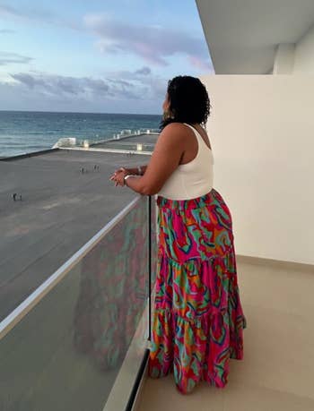reviewer lasting connected a balcony with the water presumption successful the inheritance wearing the multicolor skirt