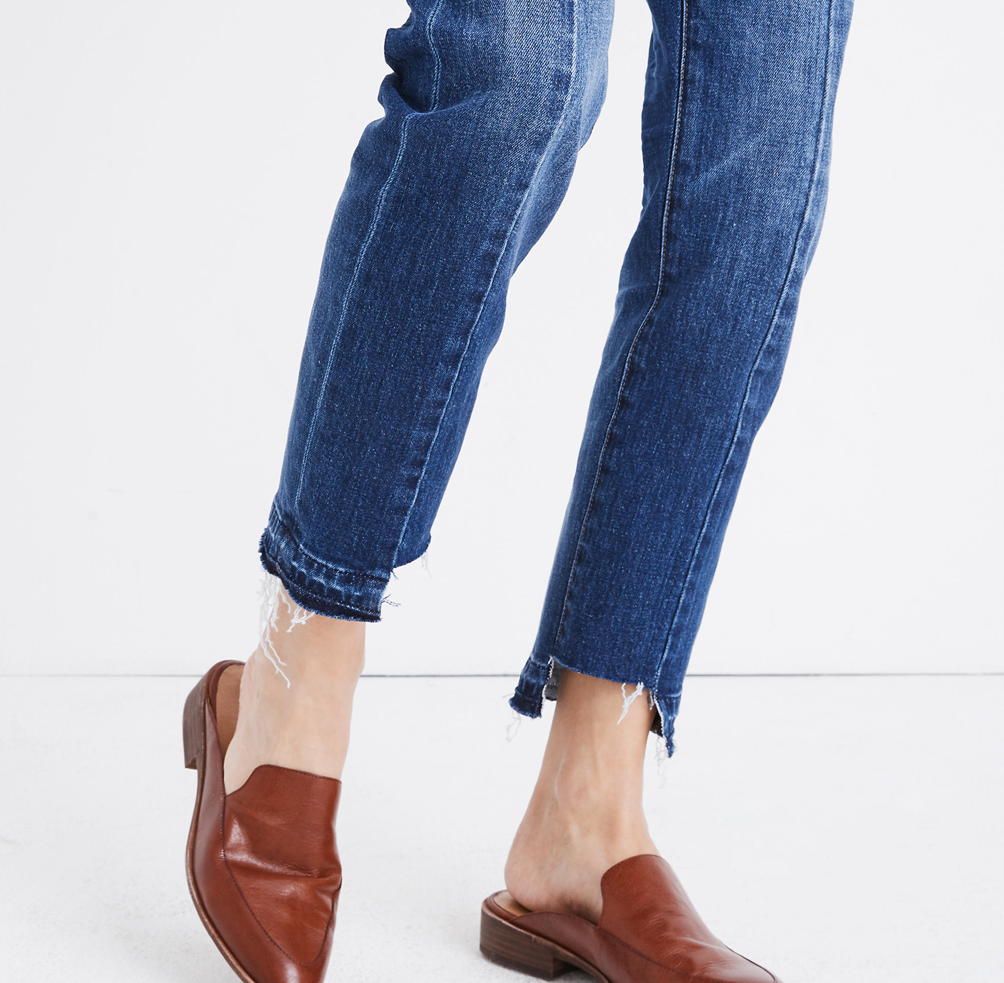 Model is wearing tan mules and blue denim jeans