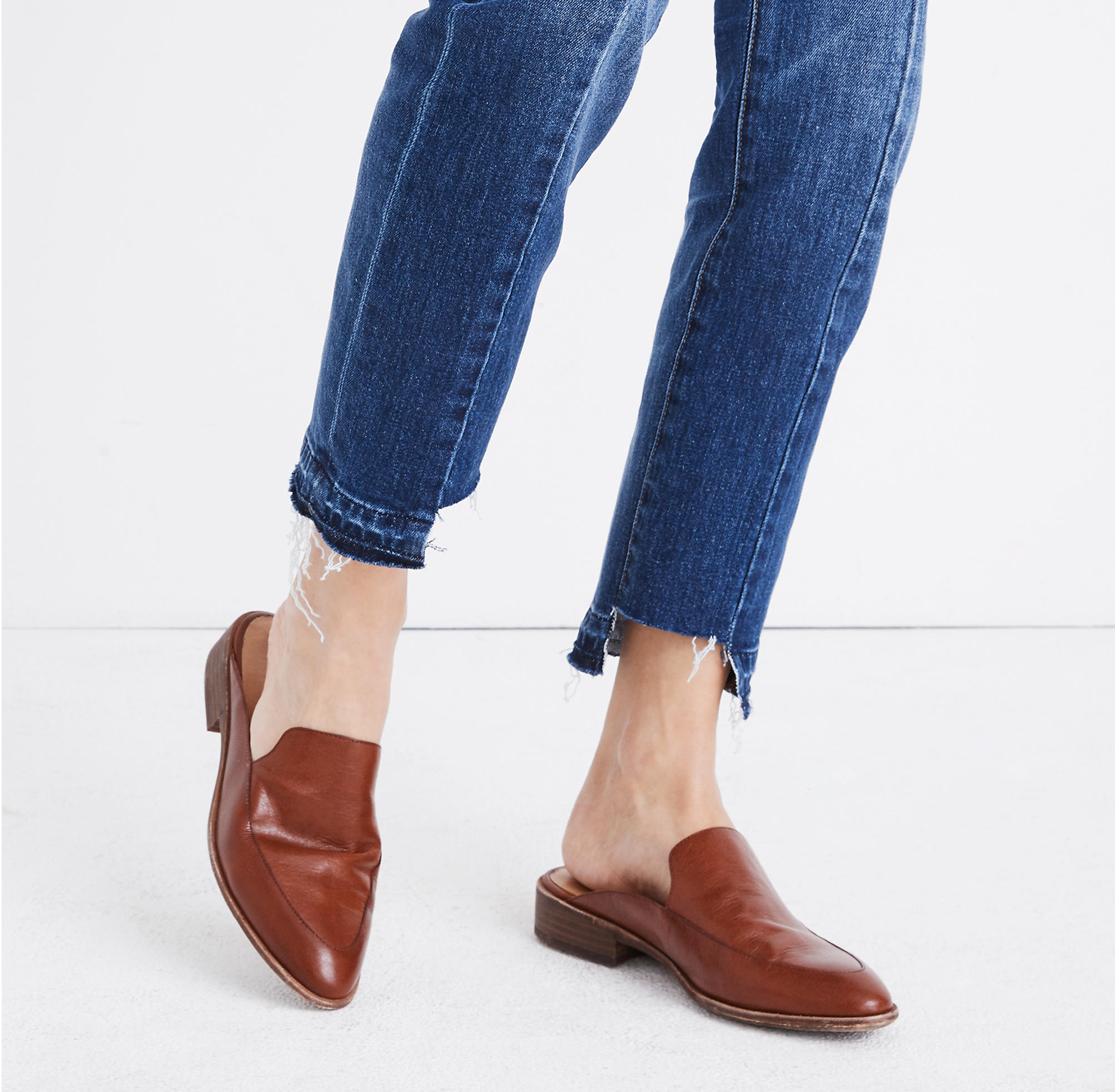 Model is wearing tan mules and blue denim jeans