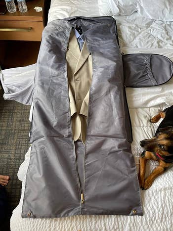 another reviewer's suit in a garment bag on a bed next to a dog