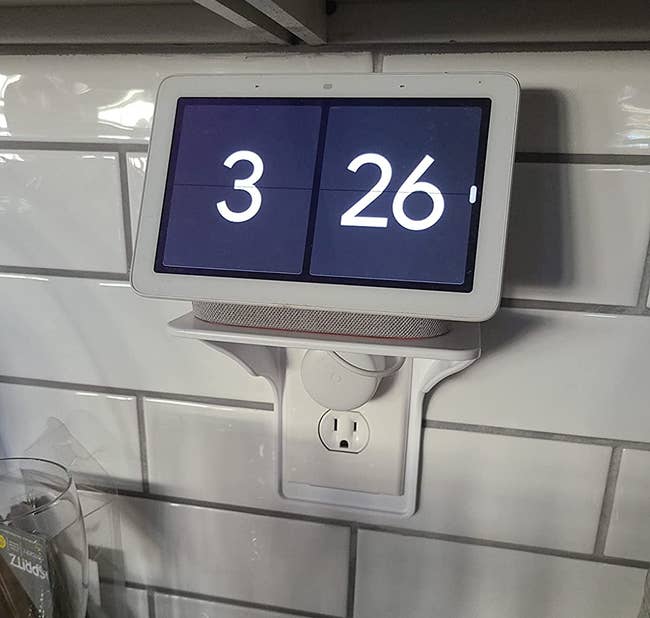 a reviewer photo of the outlet shelf installed with a digital clock screen sitting on top 