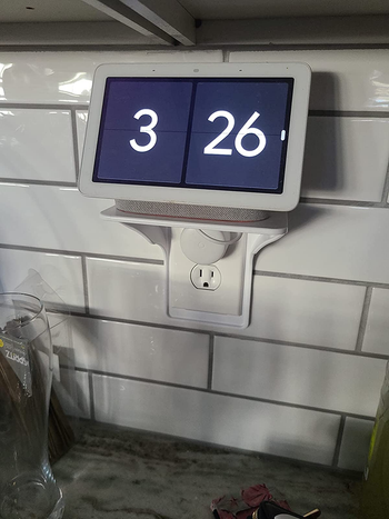 a reviewer photo of the outlet shelf installed with a digital clock screen sitting on top 