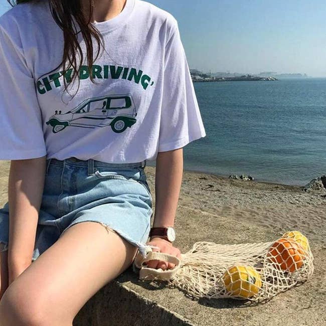 person sitting by the ocean with some fruit in the bag