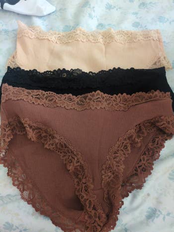 Three pairs of ribbed lace-trimmed panties successful beige, black, and brown, laid retired connected a bed
