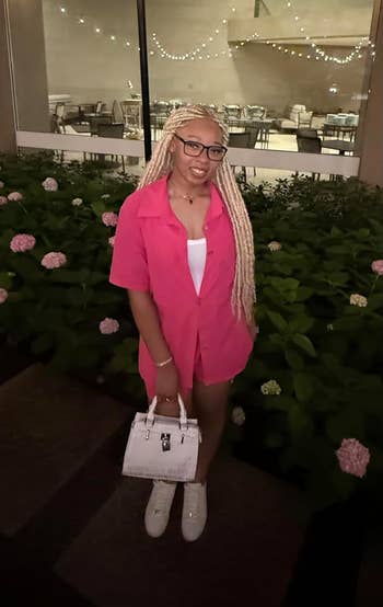 Person successful  a casual outdoor mounting  wearing a pinkish  shirt-dress, achromatic  top, and holding a achromatic  handbag