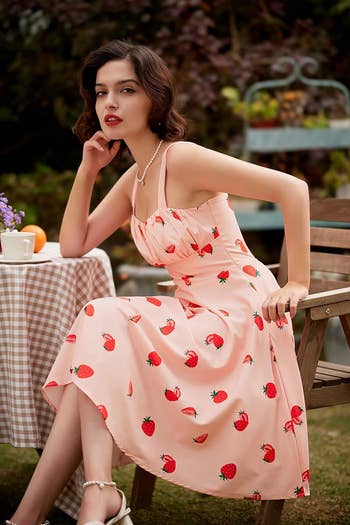 model wearing a pink dress with strawberry print on it