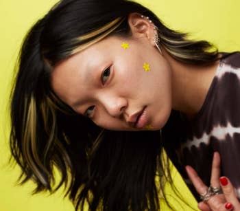 model wearing two yellow star stickers on face