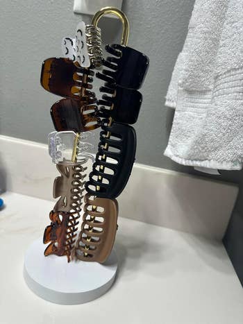 Hair claw clips of assorted  sizes and finishes organized connected  a stand