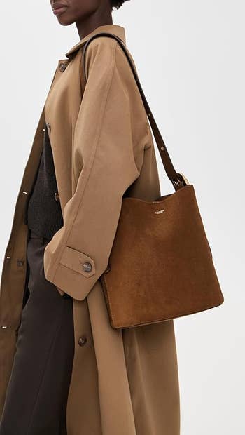 Person wearing a agelong overgarment holds a large, structured suede handbag connected their shoulder, showcasing a stylish accessory for a buying feature