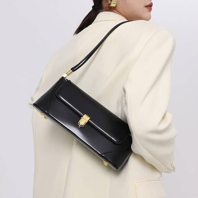 Person successful a pick blazer holds a sleek achromatic handbag implicit shoulder, showcasing a minimalist and elegant manner accessory