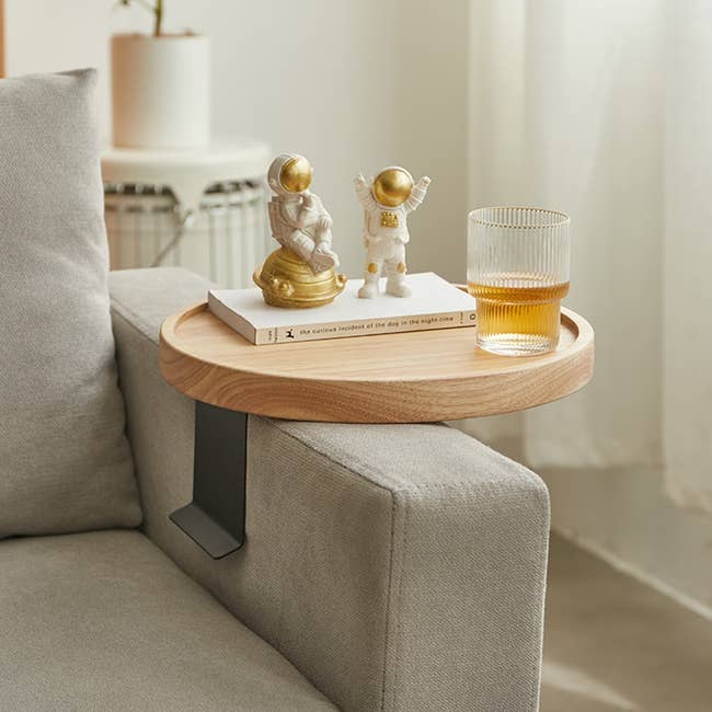 the wood clip-on table holding a drink and attached to a sofa arm 
