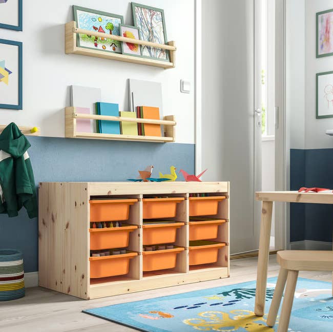 Children's country   with a woody  retention  portion   featuring orangish  bins, a tiny  table, creation  supplies, and colorful partition  decorations. Ideal for organizing toys