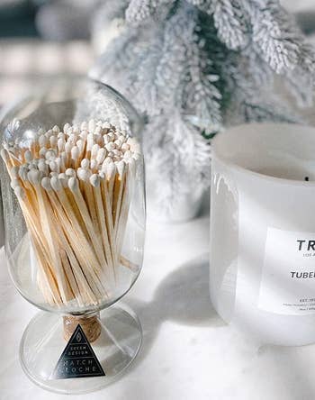 Candle and agelong matches acceptable adjacent to a frosted decorative tree, showcasing a cozy and elegant location décor point suitable for acquisition shopping