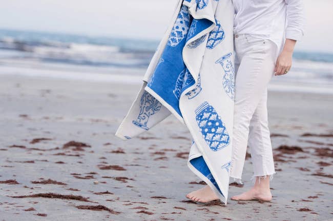 person holding decorative vase pattern blanket on a beach 
