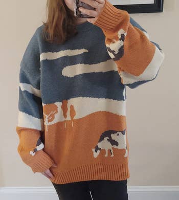reviewer in the orange and blue sweater with a cow on front