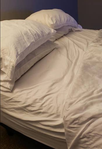 Unmade bed with white linens