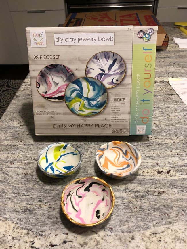 DIY clay jewelry vessel  kit with 4  finished bowls, featuring swirled patterns. Box highlights a 28-piece acceptable   for originative  location  projects