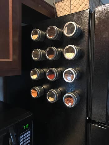 same spice containers filled with spices on side of black fridge