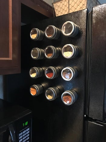 same spice containers filled with spices on side of another black fridge